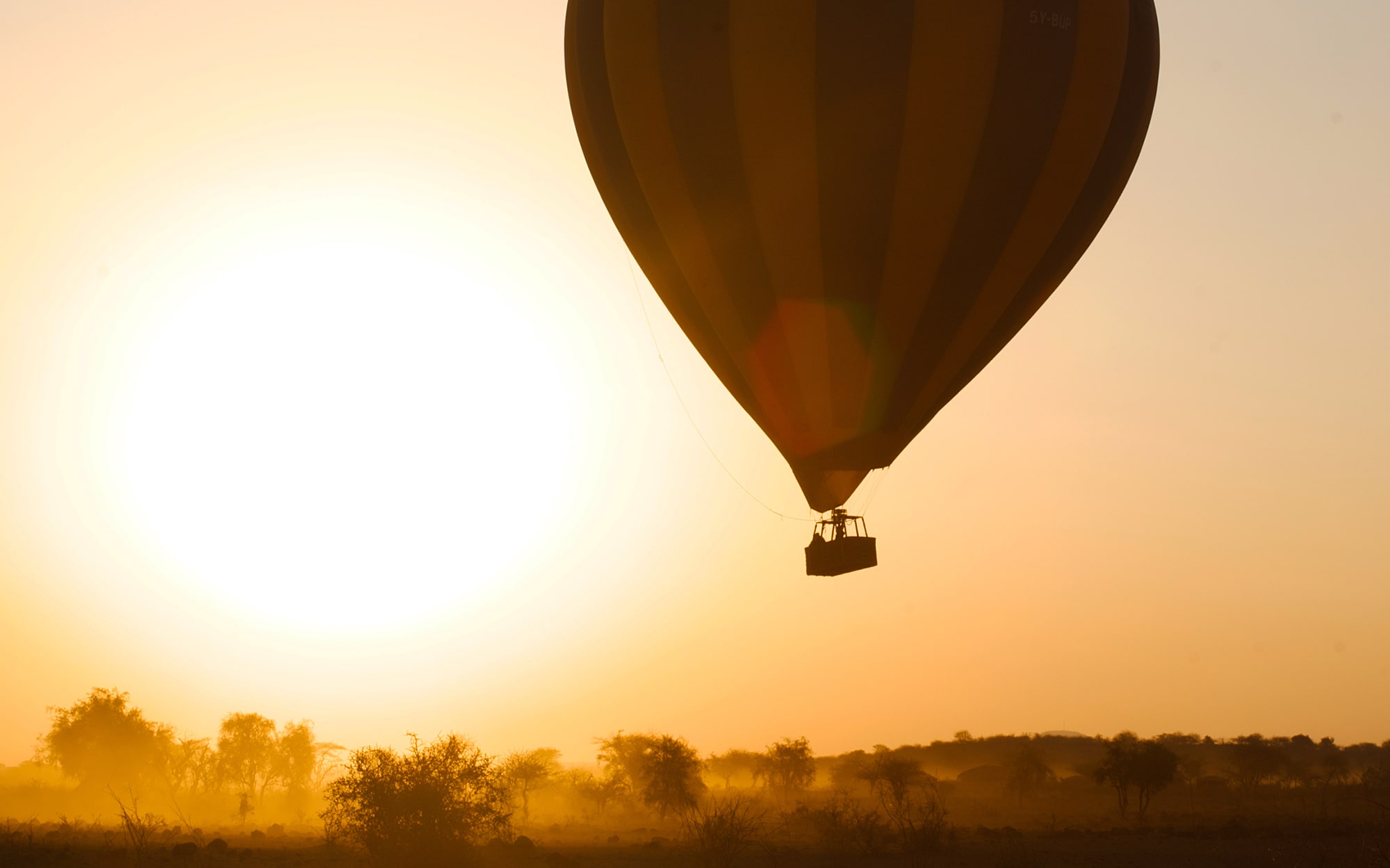 Image of the Kilimanjaro Balloon Safaris hot air balloon rising in front of a beautiful sunrise